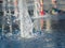 Close up view on water streams flowing out of stainless grate of dry fountain. Kids bare feet cooling near fountain