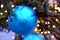 Close up view on wet misted matte blue christmas ball with water drops on christmas tree branch with lights