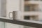 Close-up view of white blue coffee cup on sky terrace border on balcony with blurred morning city scape background.
