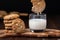 A close up view of a white chocolate chip cookie being dunked into a glass of milk with a stack of cookies beside.