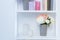 close-up view of white wooden shelves with books, candles and flowers