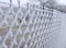 Close-up view of a wire fence with frost with ice crystals under a blue sky with a blurred background