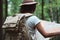 Close-up view on woman with backpack and hat hold in hands map and searching way among trees in forest