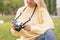 Close up view of a woman holding a mirrorless digital camera outdoors in nature