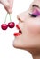 Close up view of woman with red lips eating two berries