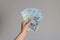 Close up view of a woman`s hand holding a pile of Romanian lei  money on a gray background . The economic impact of coronavirus