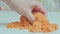 Close-up view of woman\'s hands with kinetic sand of bright orange Anti-stress