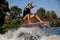 Close-up view of woman skillfully jumping on wave on surf style wakeboard.