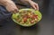 Close up view of woman stirring vegetarian salad in salad bowl.