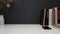 Close up view of workspace with copy space, smartphone, books, and dry roses vase on white table with black wall