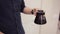 Close-up view of young barista making coffee. Man shakes up drink in little glasses teapot in the morning.