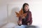 close up view of a young beautiful woman sitting on bed and holding a brown leave. Relax indoors. Autumn concept