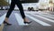 Close-up view of young businesswoman wearing shoes with heels crossing the road in busy downtown. Slow motion.