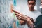 Close-up view of young colleagues hands while posted project plan on note sticky on glass wall in smart office