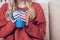 Close-up view of young girl warms hands on a Cup of tea or coffee in a cold apartment sitting on the couch. Problem of