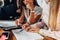 Close-up view of young women working on accounting paperwork checking and pointing at documents sitting at desk in