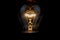 Close up of a vintage light bulb with glowing filament isolated on black background