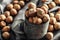 Close up of a vintage metallic mug full of hazelnuts with more nuts on a textile table cloth around it