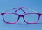 Close up of vivid pink plastic eyeglass frames on blue background.