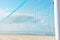 Close up of volleyball net at empty beach by ocean seaside. Blue sky sea white sand background. Summer sports recreation leisure