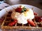 Close up waffles with cream and strawberries on white plate