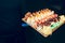 Close-up waiter holding Set of sushi red greed dragon, tuna Hokkaido California Tobico philadelphia roll buffet in night dining re
