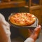 Close up of waiter serving a plate of Khachapuri - hachapuri in Adjarian. Waiter at work. Restaurant service.