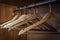 Close up of a wardrobe metal rod with empty clothes wooden hangers.