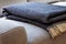 Close-up of a warm, navy blue, wool blanket with beige fringe on a comfy, gray sofa in a cozy living room interior