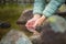 Close-up of water drops falling from female hands into a stream. The hand touches fresh water. A tourist drinks water