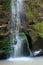 Close up of waterfall cascade over the mossy rock