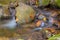 Close-up of the waterfall movement. The stream of water flows around the rock and falls down. Long exposure shot