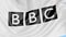 Close-up of waving flag with British Broadcasting Corporation BBC logo, seamless loop, blue background, editorial