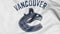 Close-up of waving flag with Vancouver Canucks NHL hockey team logo, 3D rendering