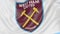 Close-up of waving flag with West Ham United FC football club logo, seamless loop, blue background. Editorial animation