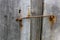 Close-up of weathered, unpainted wooden door, locked on metal hinge. Vintage background from pine shabby plank with rusty lock