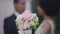 Close-up wedding bouquet with blurred African American romantic newlyweds at background. Unrecognizable couple standing