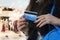Close up of well-groomed lady\'s hands with reddish manicure holding reverse side of credit card at blurred shopping centre