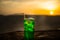 Close up wet glass of green cold mint drink, colorful orange sunset background on the terrace. Cooling summer drink. Summer fresh