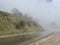 Close up of wet road in fog in mountainous terrain. Asphalt road after rain in foggy and cloudy weather.