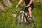 Close-up of the wheel of a bicycle and legs of the cyclist on the meadow.