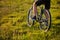 Close-up of the wheel of a bicycle and legs of the cyclist on the meadow.