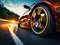 Close-up of wheel of fast sports car on highway: high speed auto in motion blur