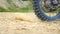 Close up wheel of powerful off-road motorcycle spinning and kicking up dry ground or dust. Professional motocross rider