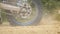 Close up wheel of powerful off-road motorcycle spinning and kicking up dry ground. Professional motocross rider starting