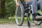 Close-up of a wheelchair from the front, a young woman sitting on it, in nature