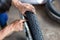 A close-up of the wheels of a motorbike is being removed by a mechanic to recap and change tires due to leaks