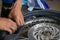 A close-up of the wheels of a motorbike is being removed by a mechanic to recap and change tires due to leaks