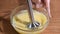 Close-up whipping homemade orange cream with a blender in a glass bowl.