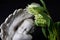 Close up of a white angel with tulip flowers on a dark background. Moment of grief at the end of a life. Last farewell. Funeral co